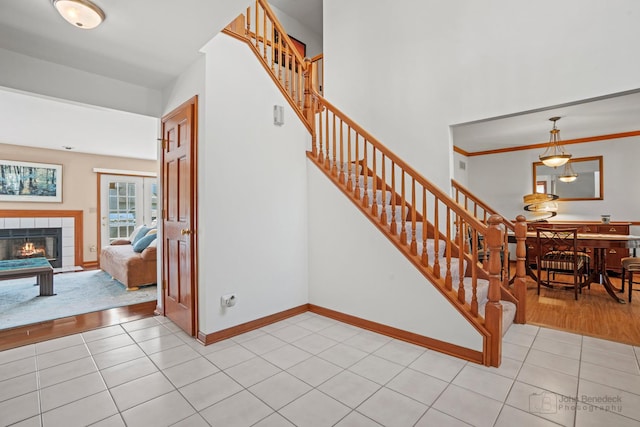 stairs featuring a tile fireplace, tile patterned flooring, and baseboards