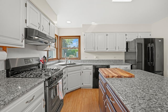 kitchen with black appliances, under cabinet range hood, a sink, and white cabinets