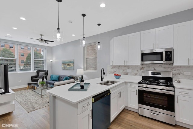kitchen featuring open floor plan, backsplash, ceiling fan, stainless steel appliances, and a sink