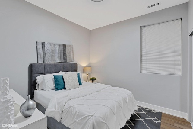 bedroom featuring visible vents, baseboards, and wood finished floors