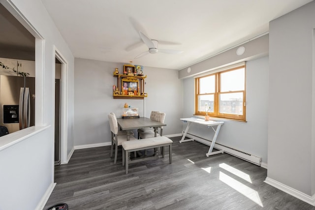 dining room featuring dark wood-style flooring, a ceiling fan, a baseboard heating unit, and baseboards