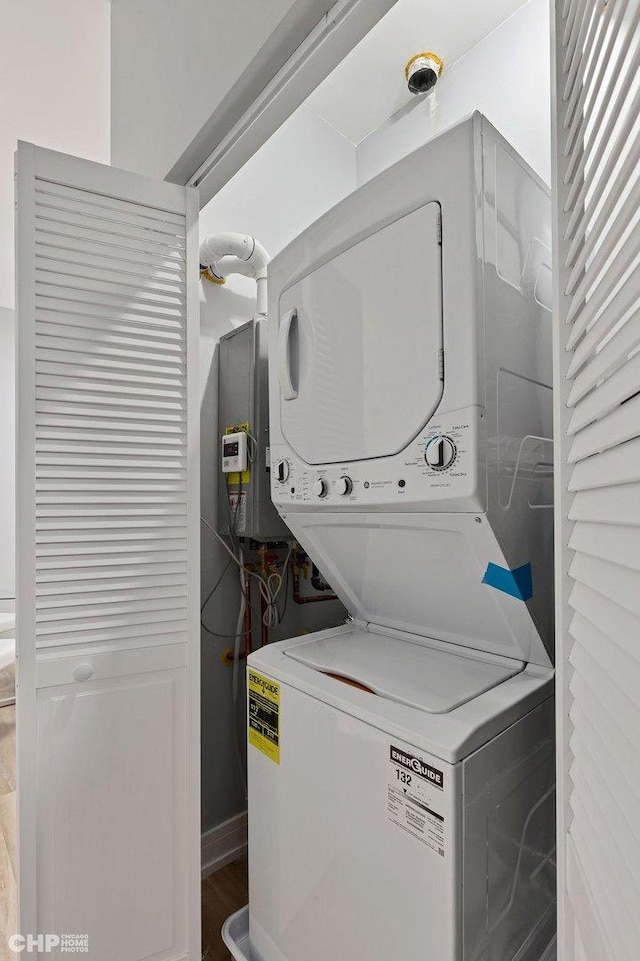 clothes washing area featuring stacked washer / dryer and laundry area