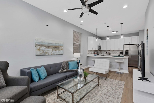living area featuring light wood finished floors, ceiling fan, baseboards, and recessed lighting