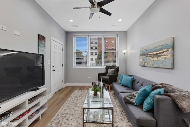 living area featuring visible vents, ceiling fan, wood finished floors, and baseboards
