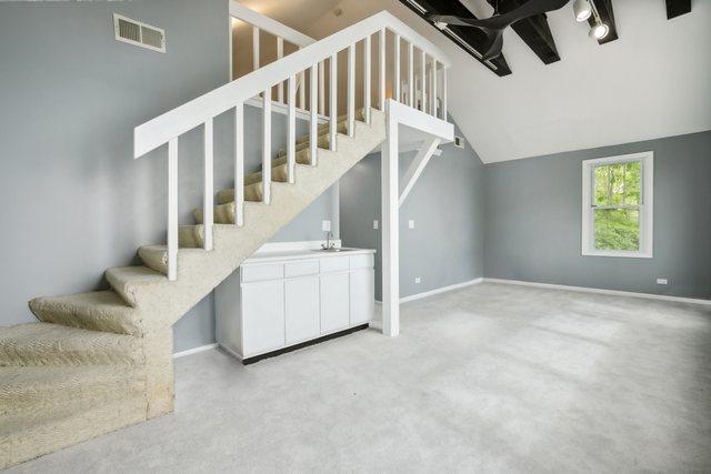 135 Cora Ave, Fox Lake, IL 60020 - unfurnished living room with stairs, a sink, vaulted ceiling, and baseboards