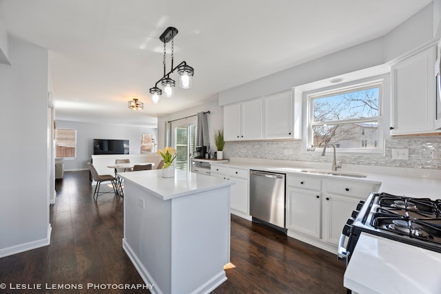 kitchen featuring tasteful backsplash, a sink, dishwasher, gas range oven, and a kitchen island