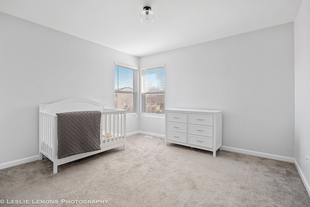 unfurnished bedroom with a nursery area, baseboards, and carpet flooring
