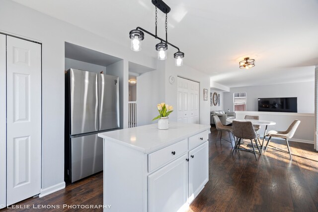 kitchen featuring a center island, open floor plan, white cabinetry, dark wood-style flooring, and freestanding refrigerator