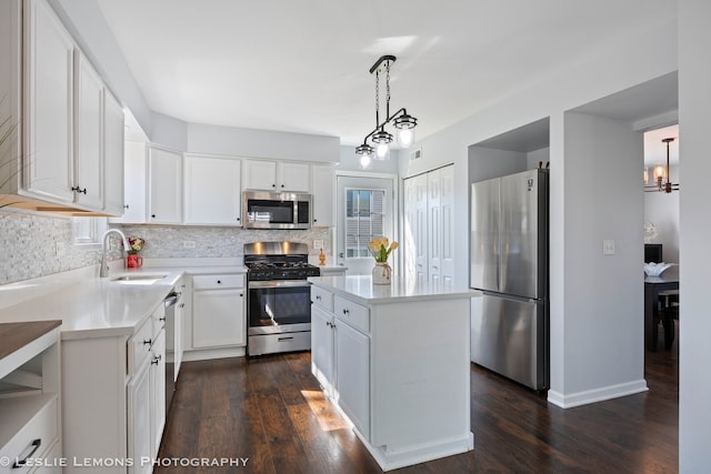 kitchen featuring tasteful backsplash, a sink, a chandelier, dark wood finished floors, and appliances with stainless steel finishes