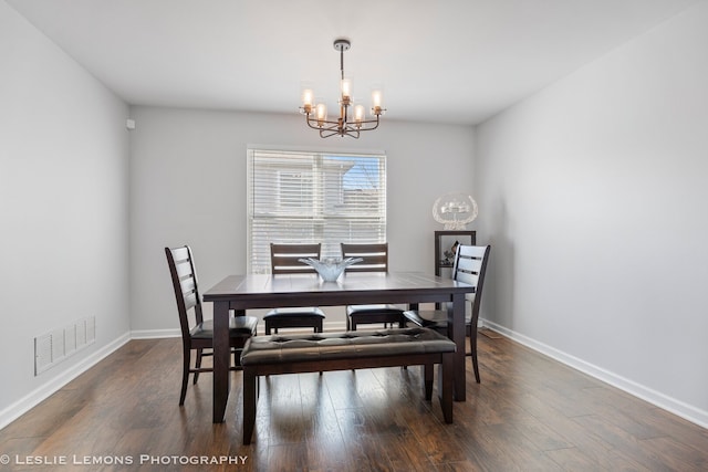 dining area featuring a chandelier, wood finished floors, visible vents, and baseboards