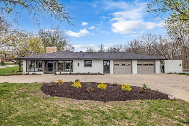 view of front of home with concrete driveway, a front lawn, a garage, and a chimney