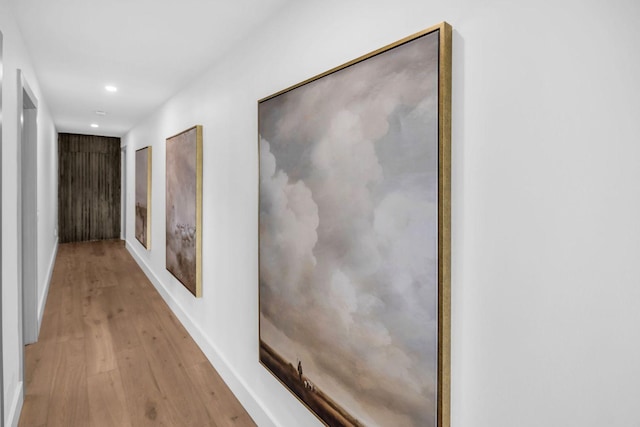 hallway featuring baseboards, wood finished floors, and recessed lighting