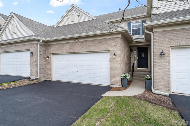 exterior space featuring brick siding, an attached garage, aphalt driveway, and a shingled roof