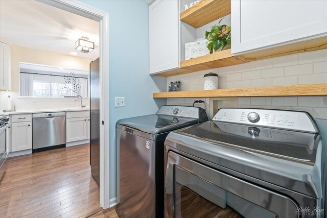 laundry area featuring cabinet space, hardwood / wood-style floors, a sink, and washer and clothes dryer