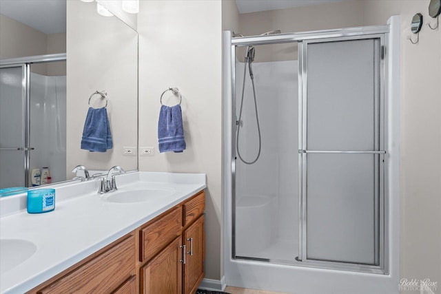 full bath featuring a shower stall, a sink, and double vanity