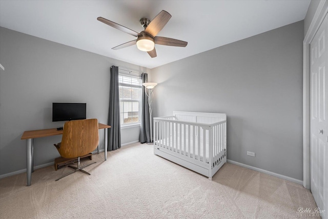 carpeted bedroom featuring baseboards, a ceiling fan, and a crib