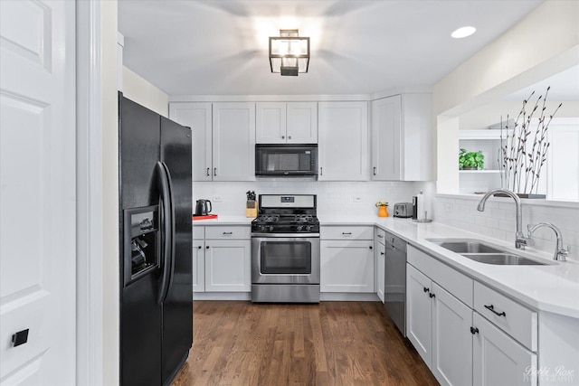 kitchen with a sink, white cabinets, black appliances, light countertops, and backsplash