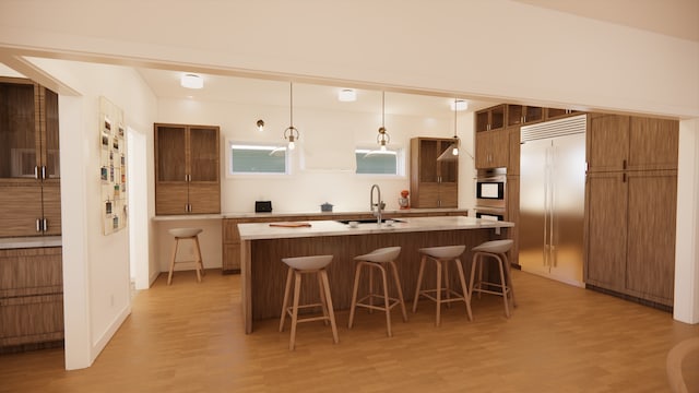 kitchen with a sink, light countertops, a kitchen breakfast bar, light wood-style flooring, and a center island with sink