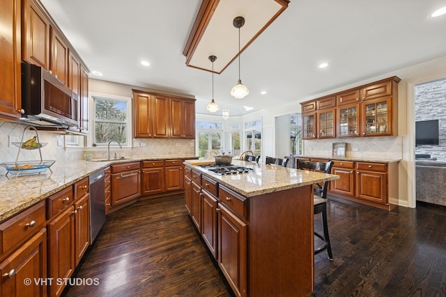 kitchen with decorative backsplash, a breakfast bar, a sink, dark wood finished floors, and stainless steel appliances