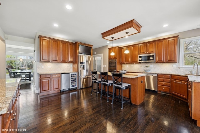 kitchen featuring appliances with stainless steel finishes, a center island, a healthy amount of sunlight, wine cooler, and dark wood-style floors