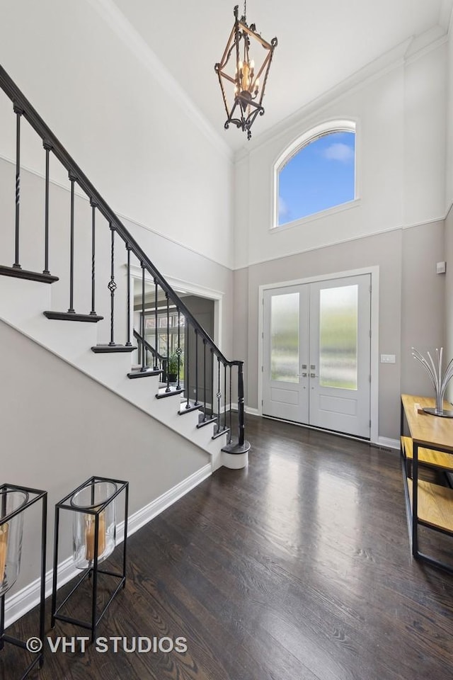 entryway with ornamental molding, wood finished floors, stairway, and a towering ceiling