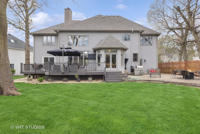 rear view of house featuring a wooden deck, a chimney, and a yard