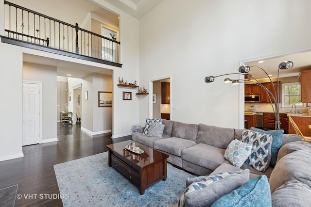 living room with recessed lighting, baseboards, a high ceiling, and dark wood finished floors