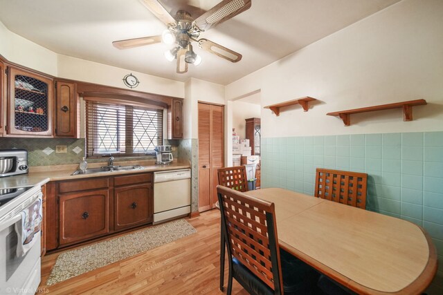 kitchen featuring open shelves, a sink, white appliances, tile walls, and light wood-style flooring
