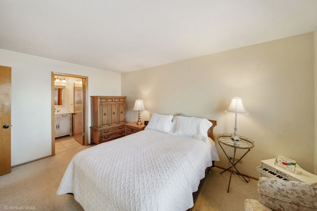 bedroom with ensuite bath, light carpet, and baseboards