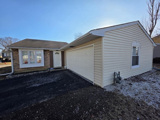 view of front of house featuring roof with shingles, an attached garage, and aphalt driveway