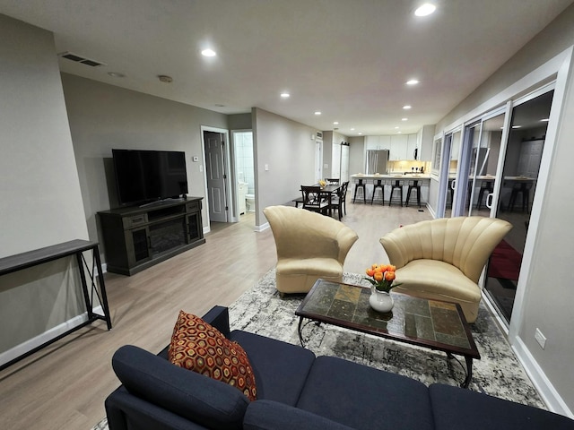 living room with visible vents, baseboards, and light wood finished floors