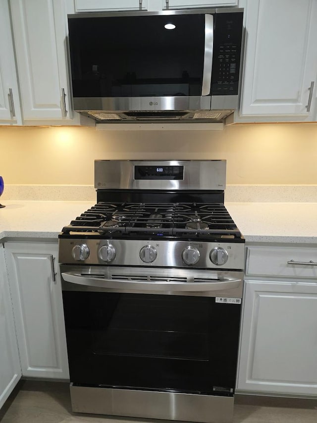 kitchen featuring appliances with stainless steel finishes, light stone counters, and white cabinets