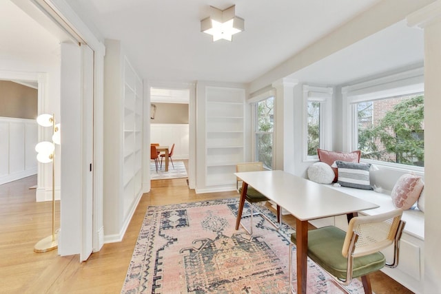 home office featuring light wood finished floors and built in shelves