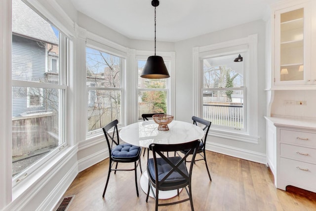 dining space with light wood-type flooring, baseboards, and visible vents