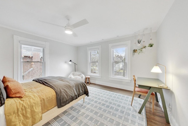 bedroom featuring crown molding, baseboards, a ceiling fan, and wood finished floors