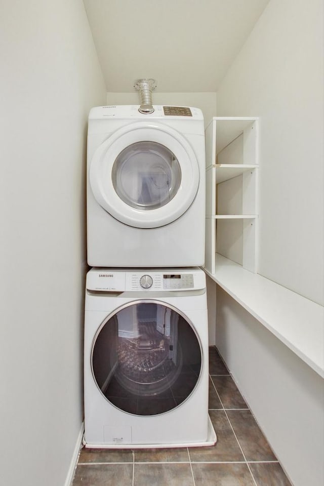 clothes washing area featuring tile patterned floors, stacked washing maching and dryer, and laundry area