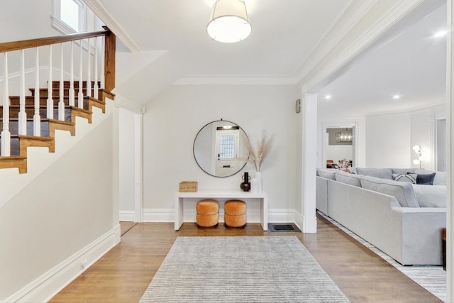 entrance foyer featuring wood finished floors, ornamental molding, visible vents, and stairway