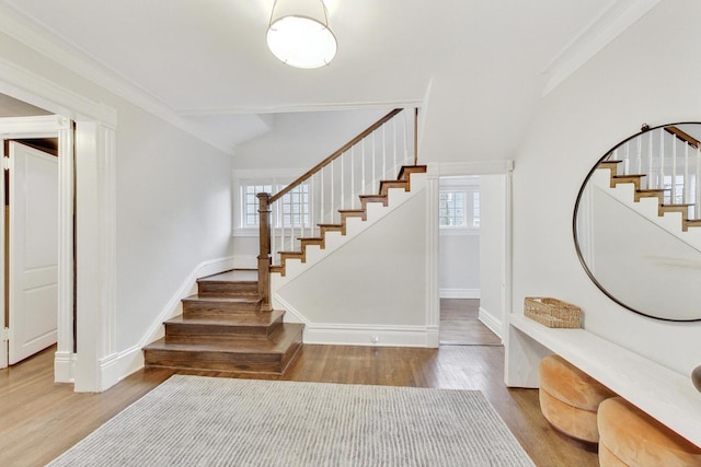 foyer entrance featuring baseboards, wood finished floors, and stairs