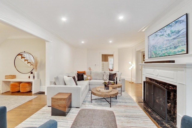 living area with wood finished floors, recessed lighting, crown molding, and a premium fireplace