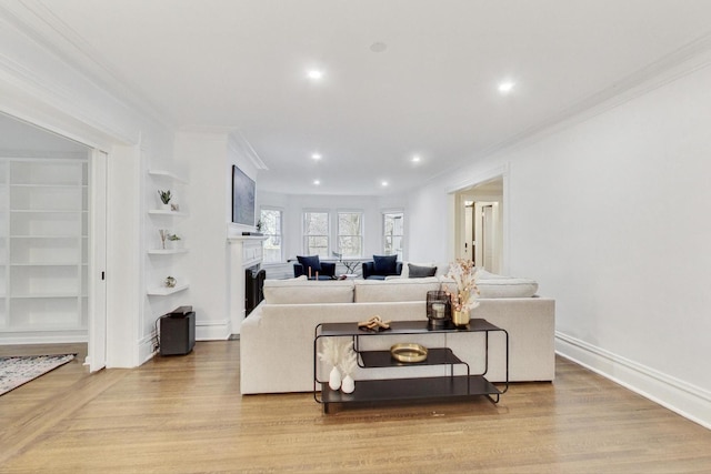 living area featuring light wood-style floors, recessed lighting, a fireplace, and ornamental molding