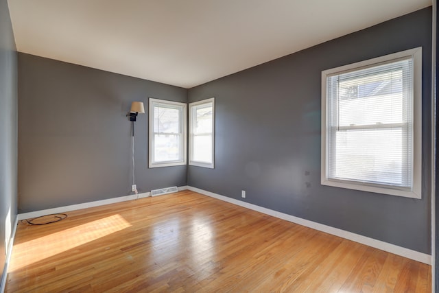 unfurnished room with light wood-type flooring, baseboards, and visible vents
