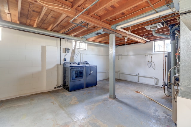 below grade area with washing machine and clothes dryer and concrete block wall