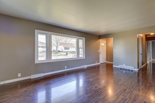 interior space with baseboards, dark wood-style flooring, and visible vents