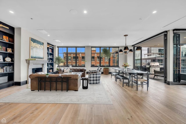 living area featuring built in features, a fireplace, recessed lighting, and hardwood / wood-style floors