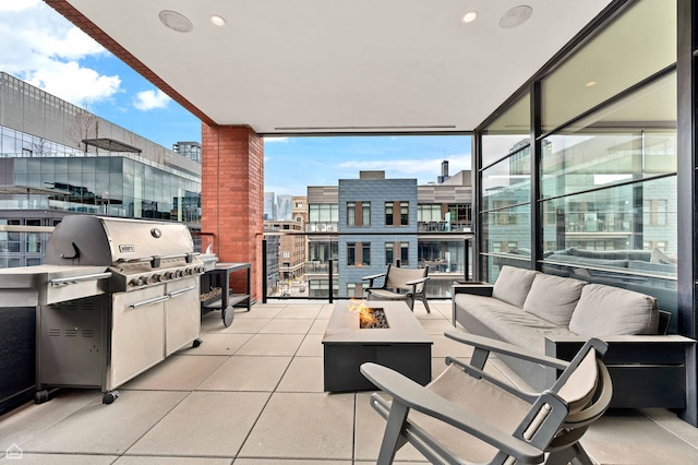 view of patio with area for grilling, a view of city, a balcony, and an outdoor living space with a fire pit