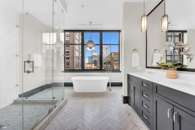 bathroom with double vanity, a sink, a freestanding tub, and a stall shower