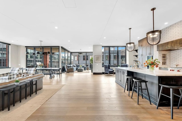 kitchen with light countertops, a wall of windows, a breakfast bar, and light wood-style flooring