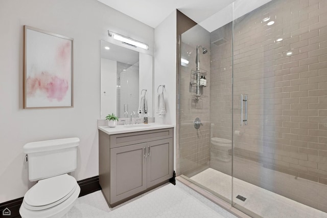 bathroom with vanity, baseboards, toilet, and tiled shower