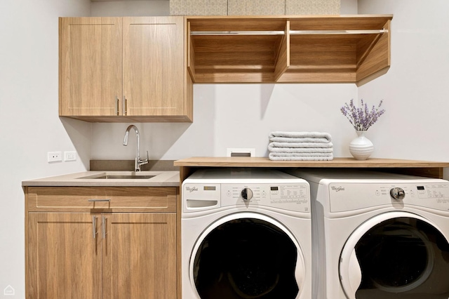 clothes washing area featuring a sink, separate washer and dryer, and cabinet space