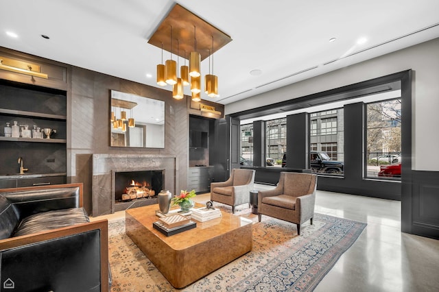 interior space with built in features, concrete flooring, a notable chandelier, recessed lighting, and a premium fireplace